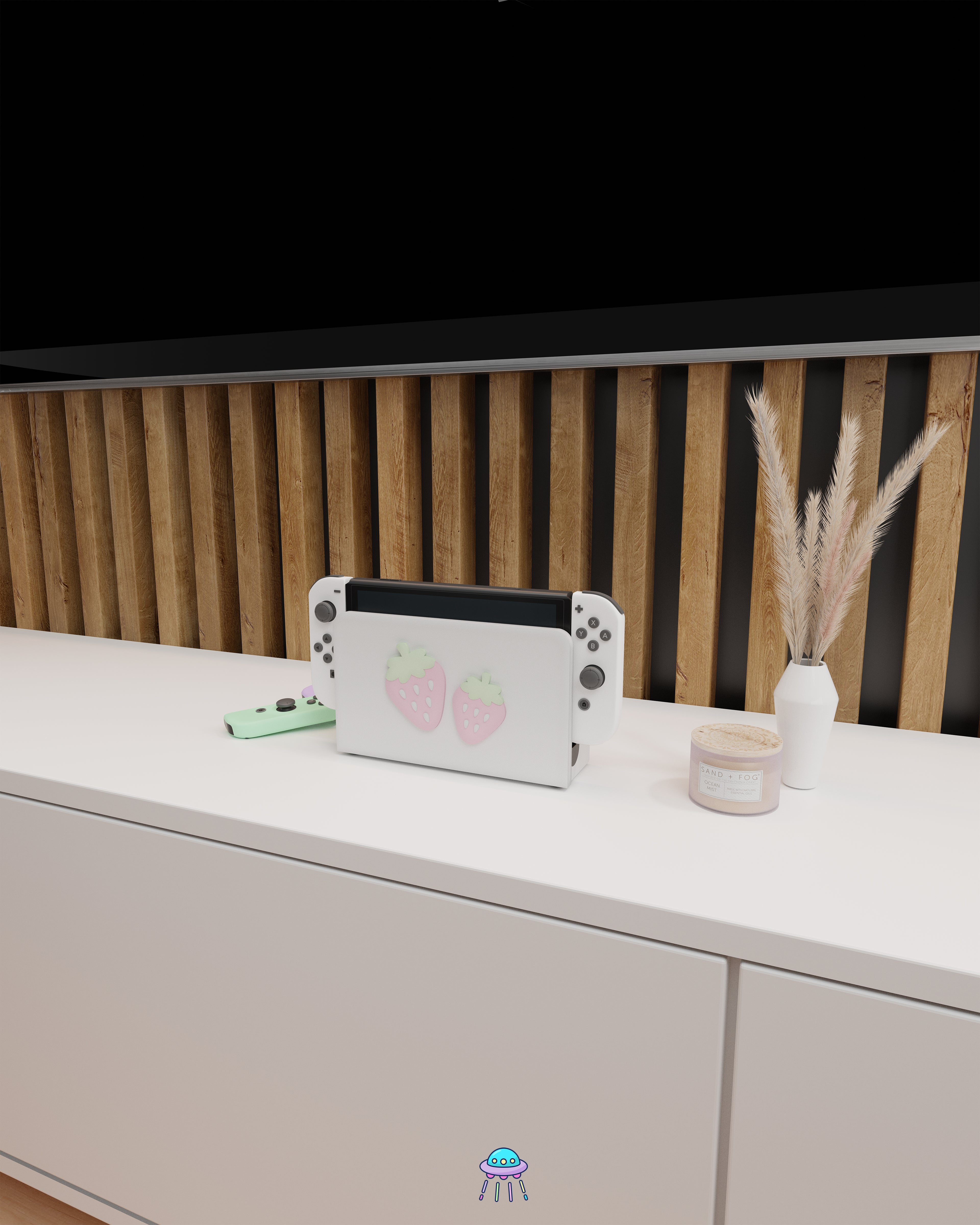 Wider angle of a Nintendo Switch with Joy-Con controllers docked in a customised dock featuring a white PLA filament cover and pink base. The cover has two strawberry designs on the front—one larger to the left and a smaller strawberry to the right. The setup is placed on a white cabinet with a wooden panel background and decorative items nearby, including a candle, a vase with dried pampas grass, and an additional pair of Joy-Con controllers.