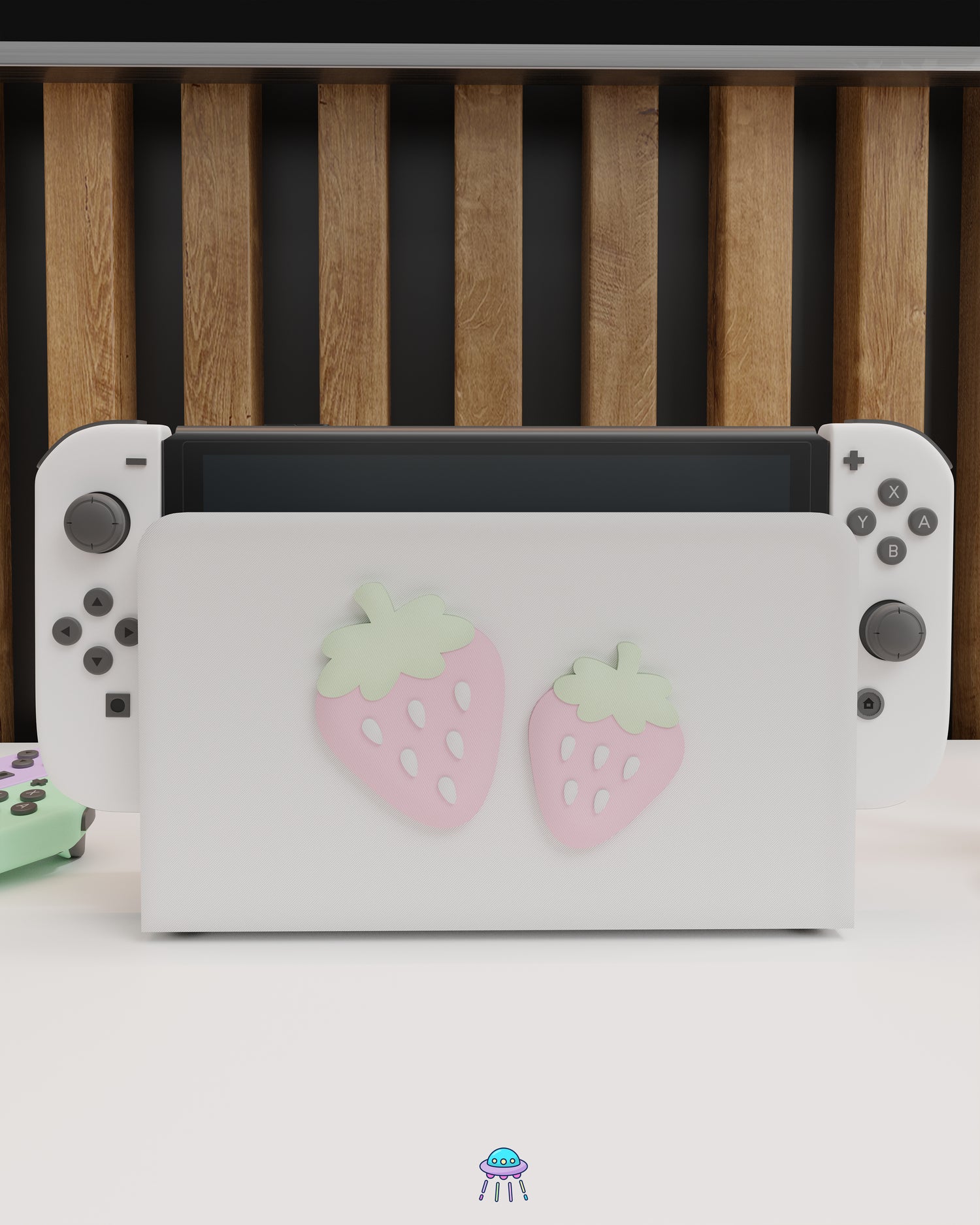 Front angle of a Nintendo Switch with Joy-Con controllers docked in a customised dock featuring a white PLA filament cover and pink base. The cover has two strawberry designs on the front—one larger to the left and a smaller strawberry to the right. The setup is placed on a white cabinet with a wooden panel background and decorative items nearby, including a candle and a vase with dried pampas grass.