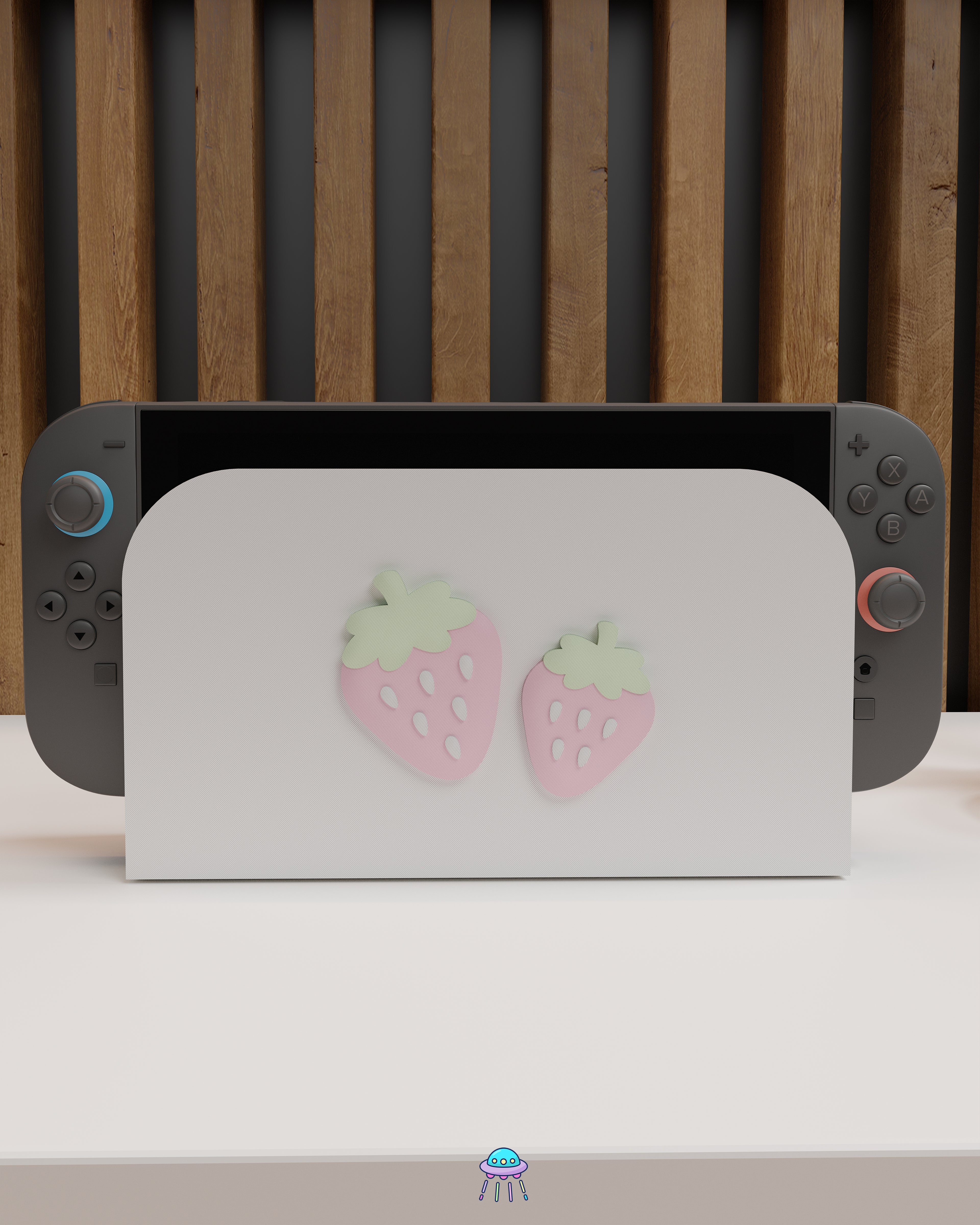 Front view of a Nintendo Switch 2 with Joy-Con controllers docked in a customised dock featuring a white PLA filament cover and pink base. The cover has two strawberry designs on the front—one larger to the left and a smaller strawberry to the right. The setup is placed on a white cabinet with a wooden panel background.